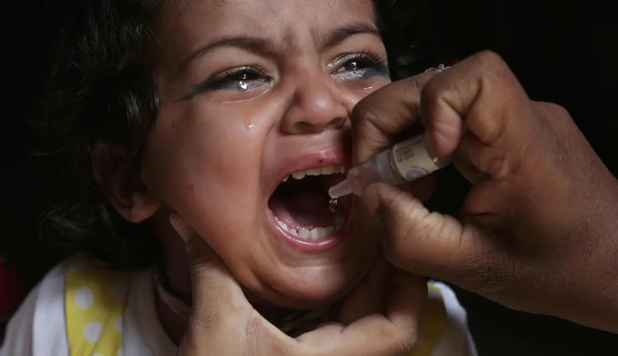 Seorang anak menangis saat diberikan vaksin polio oleh pekerja kesehatan di Lahore, Pakistan, (9/4). Pakistan meluncurkan vaksinasi polio baru, yang bertujuan agar 38,7 juta anak di bawah usia 5 tahun mendapatkan vaksin tersebut. (AP Photo/KM Chaudary)