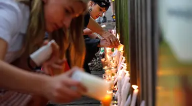 Para pelajar menyalakan lilin saat mengenang korban penembakan di luar Masjid Al Noor, Christchurch, Selandia Baru, Senin (18/3). Penembakan tersebut merupakan serangan terburuk dalam sejarah Selandia Baru modern. (AP Photo/Vincent Yu)
