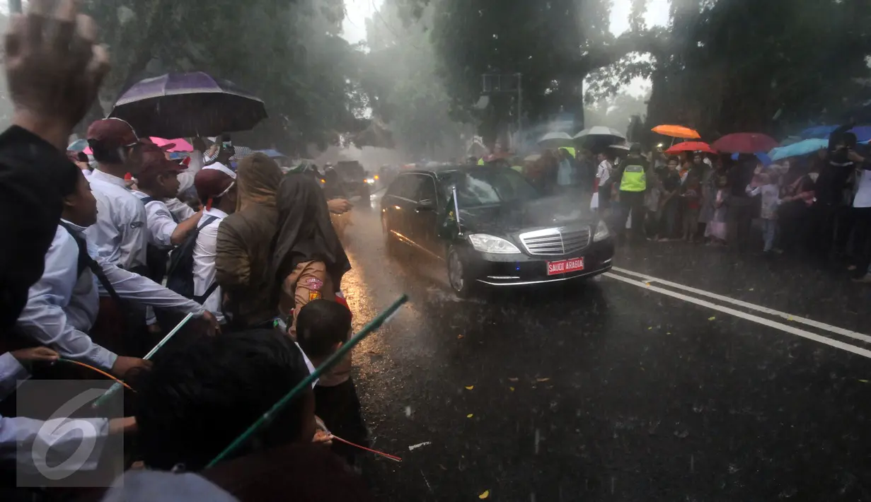 Pelajar dan warga menyambut kedatangan mobil bertuliskan Saudi Arabia di sekitar Istana Bogor, Rabu (1/3). Kedatangan Raja Salman bin Abdulaziz ke Istana Bogor disambut puluhan ribu pelajar dan warga. (Liputan6.com/Helmi Fithriansyah) 