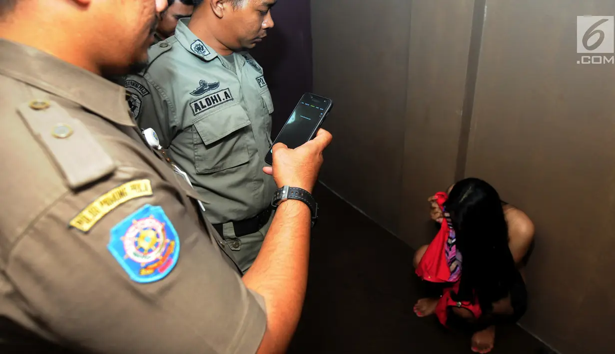 Petugas Satpol PP mengintrogasi seorang wanita selama razia panti pijat di BSD, Tangerang Selatan, Selasa (25/6/2019). Dalam razia tersebut puluhan wanita diamankan karena tidak bisa menunjukan kartu identitas. (merdeka.com/Arie Basuki)
