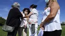 Perempuan yang kehilangan ayah mereka karena COVID-19 menambahkan bendera putih dengan namanya ke lapangan yang dipenuhi bendera untuk mewakili korban virus corona di Brasil selama protes terhadap kebijakan kesehatan pemerintah di luar Kongres di Brasilia, Jumat (15/10/2021). (AP Photo/Eraldo Peres