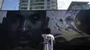 Seniman Nikkolas Smith melihat mural yang menggambarkan Kobe Bryant dan putrinya, Gianna, di Los Angeles, Rabu, 24 Agustus 2022. Berukuran 125 kaki kali 32 kaki, mural tersebut menampilkan potret Bryant, yang meninggal pada tahun 2020 pada usia 41 tahun dalam kecelakaan helikopter. (AP Photo/Jae C. Hong)