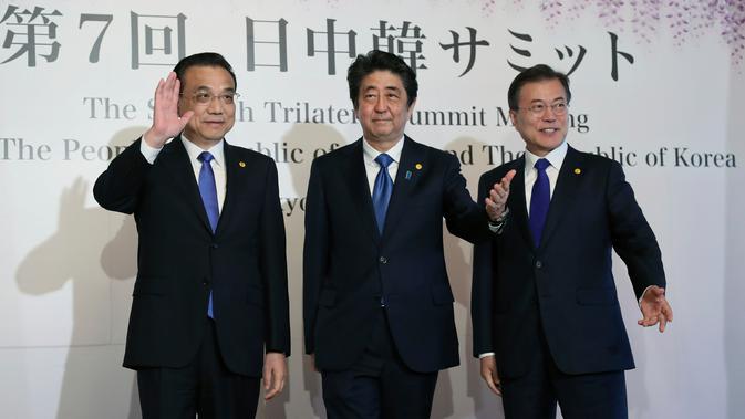 Perdana Menteri China Li Keqiang, Perdana Menteri Jepang Shinzo Abe dan Presiden Korea Selatan Moon Jae-in menyapa awak media usai melakukan pertemuan tingga negara di Tokyo, Jepang (9/5). (AP Photo/Eugene Hoshiko, Pool)
