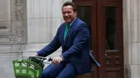 Gubernur California ke-38, Arnold Schwarzenegger tersenyum saat mengendarai sepeda untuk bertemu Walikota Paris, Anne HIdalgo di Paris (11/12). Schwarzenegger berada di Paris untuk menghadiri pertemuan puncak iklim One Planet. (AP Photo / Thibault Camus)