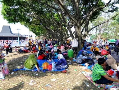 Sejumlah pengunjung beristirahat di area wisata Taman Mini Indonesia Indah, Jakarta, Minggu (19/07/2015). Makan bersama sambil menggelar tiker di tempat wisata menjadi pilihan warga yang mengunjungi tempat wisata TMII. (Liputan6.com/Yoppy Renato)