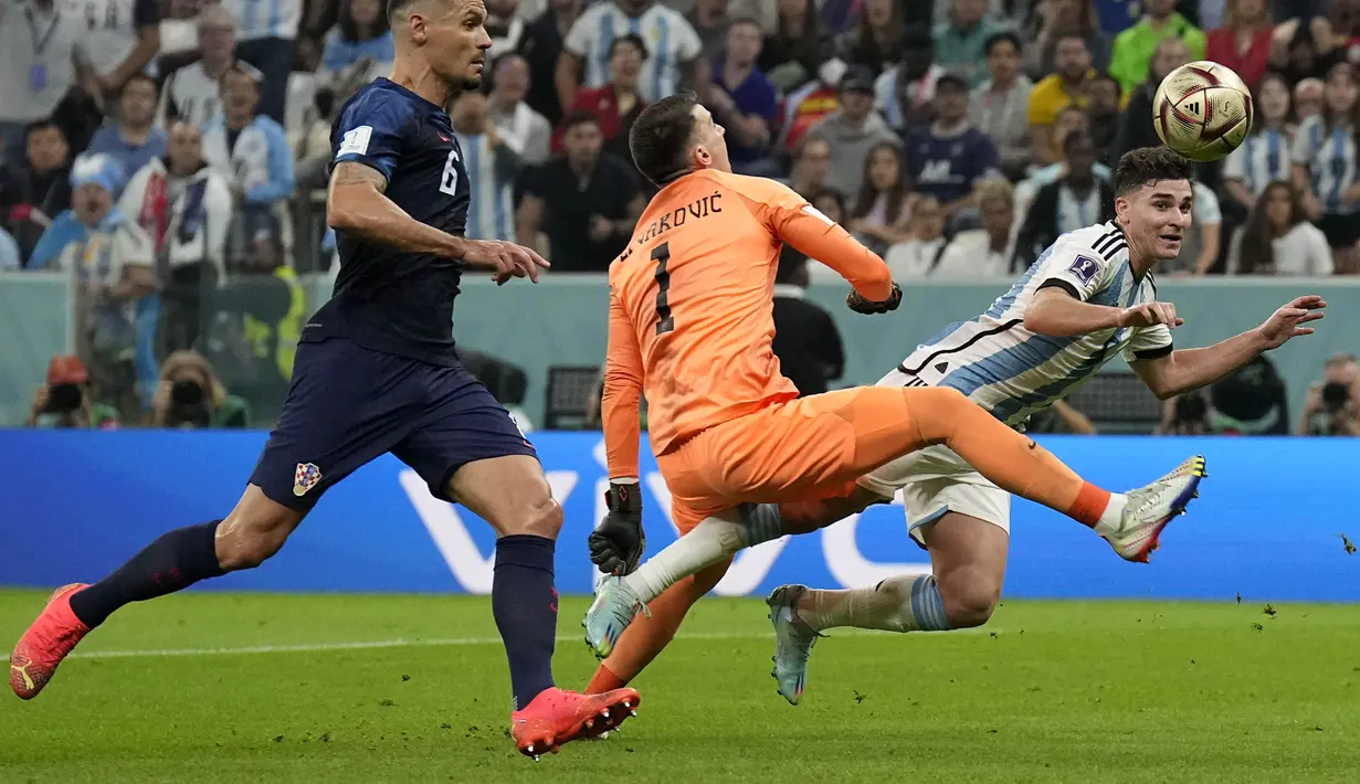 <p>Pemain Argentina, Julian Alvarez (kanan) dilanggar oleh kiper Kroasia, Dominik Livakovic di dalam kotak penalti saat laga semifinal Piala Dunia 2022 yang berlangsung di Lusail Stadium, Qatar, Selasa (13/12/2022) waktu setempat. (AP Photo/Martin Meissner)</p>