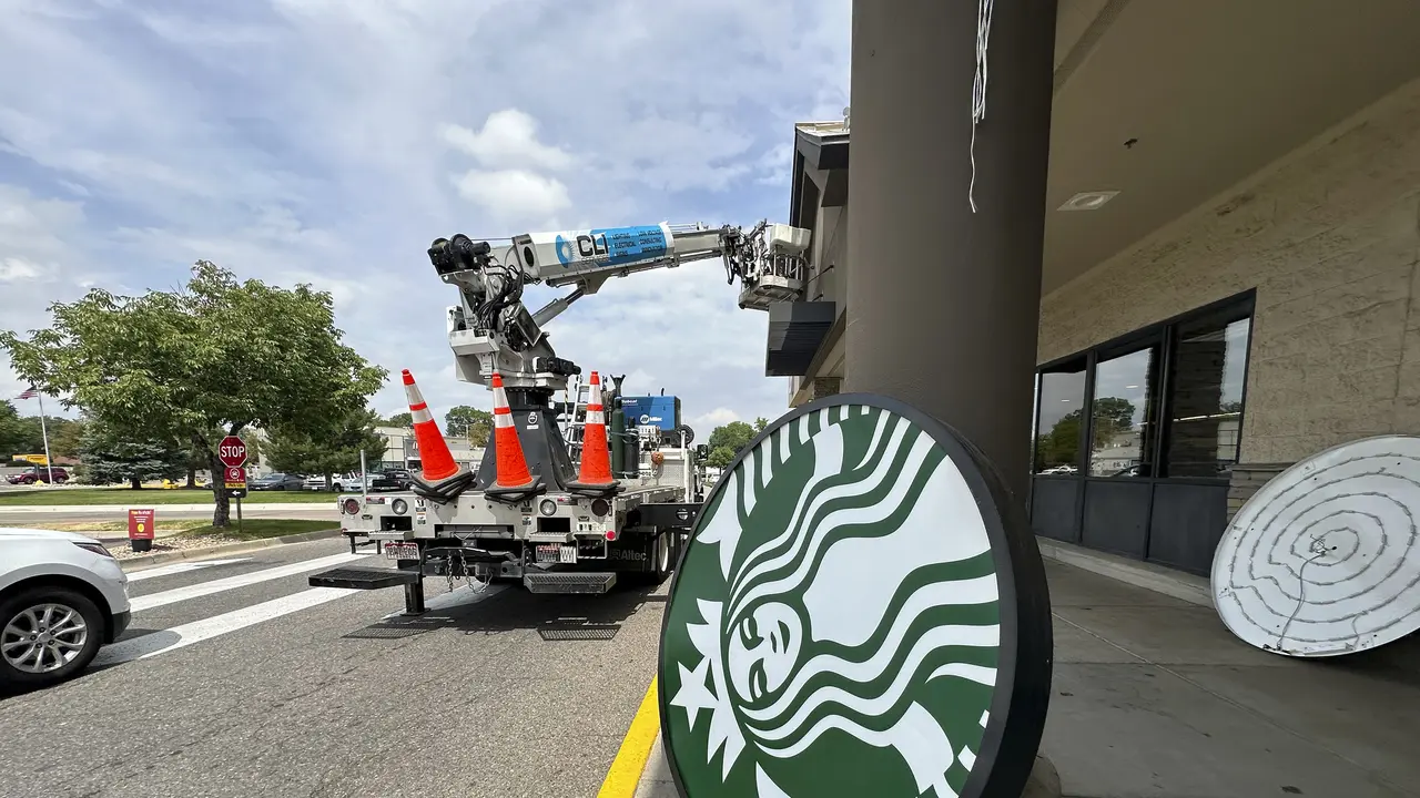Seorang pekerja membongkar papan nama Starbucks