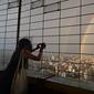 Seorang wanita mengambil foto pelangi ganda melalui pagar di Central Television Tower di Beijing (26/8/2021). Keindahan pelangi ganda dimanfaatkan warga Beijing untuk diabadikan lewat foto dan berfoto dengan latar pelangi itu. (AFP/Jade Gao)