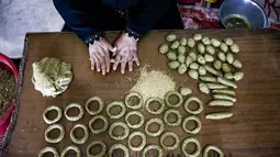 Kesibukan anggota keluarga Palestina menyiapkan kue-kue tradisional untuk dijual sebagai persiapan liburan Idul Fitri mendatang, di kota Rafah, Jalur Gaza, Selasa (4/5/2021). Pembuatan kue tradisional untuk Hari Raya Idul Fitri atau Lebaran yang menandai akhir bulan Ramadhan. (KATA KHATIB/AFP)