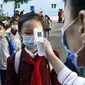 Seorang guru mengukur suhu tubuh seorang siswi untuk membantu mengekang penyebaran virus corona sebelum memasuki Sekolah Dasar Kim Song Ju di Distrik Pusat di Pyongyang, Korea Utara, Rabu, 13 Oktober 2021. (Foto AP/Cha Song Ho, File)