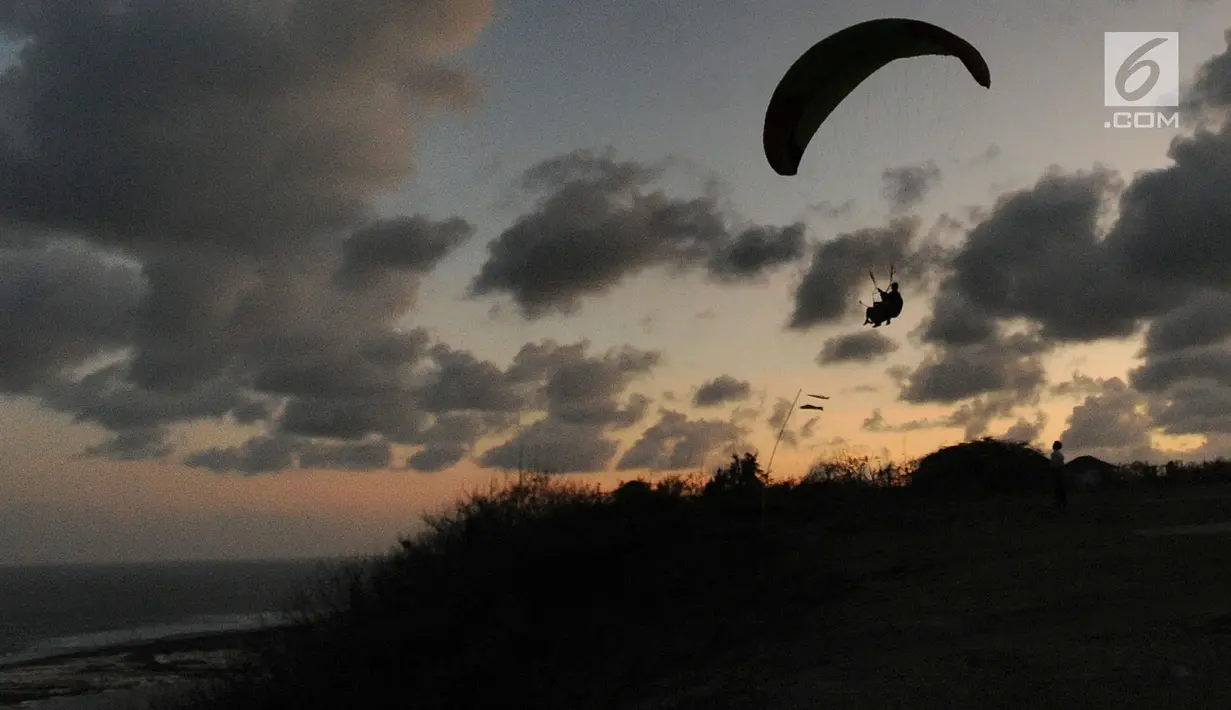 Wisatawan melakukan tandem paralayang di Bukit Riug, Nusa Dua, Bali (30/6). Kegiatan paralayang tandem dengan mengandalkan angin pantai sudah lebih dari satu tahun digemari para wisatawan mancanegara dan lokal. (Merdeka.com/Arie Basuki)