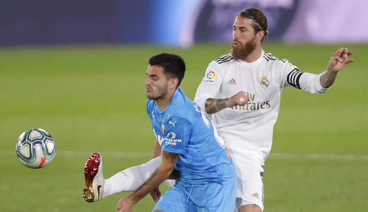 Pemain Real Madrid Sergio Ramos (kanan) berebut bola dengan pemain Valencia Maxi Gomez pada pertandingan La Liga Spanyol di Estadio Alfredo Di Stefano, Madrid, Spanyol, Kamis (18/6/2020). Real Madrid menang 3-0 lewat dua gol Karim Benzema dan satu gol Marco Asensio. (AP Photo Manu Fernandez)
