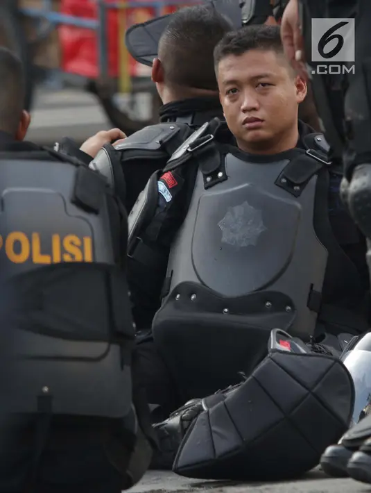 Anggota kepolisian dari satuan Brimob beristirahat saat menjaga aksi unjuk rasa yang dilakukan Gerakan Nasional Kedaulatan Rakyat di depan Gedung Bawaslu, Jakarta, Selasa (21/5/2019). Ribuan aparat keamanan gabungan diterjunkan untuk mengamankan jalannya aksi. (Liputan6.com/Helmi Fithriansyah)