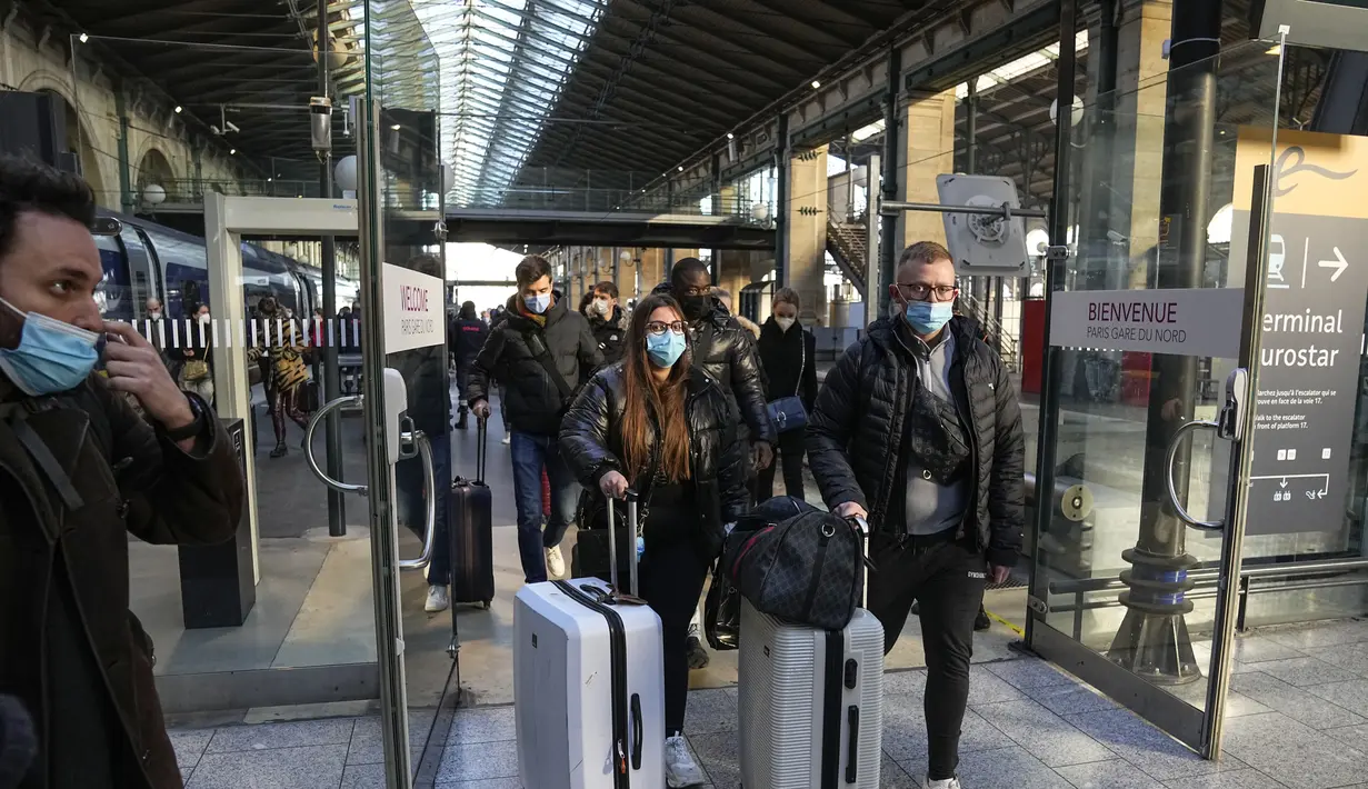 Penumpang yang tiba dari London dengan kereta Eurostar, mengenakan masker untuk melindungi dari COVID-19 keluar dari gerbang kedatangan di stasiun kereta Gare du Nord, Paris, Jumat (14/1/2022). Prancis telah mencabutnya Larangan COVID terhadap turis Inggris mulai (14/1). (AP Photo/Michel Euler)