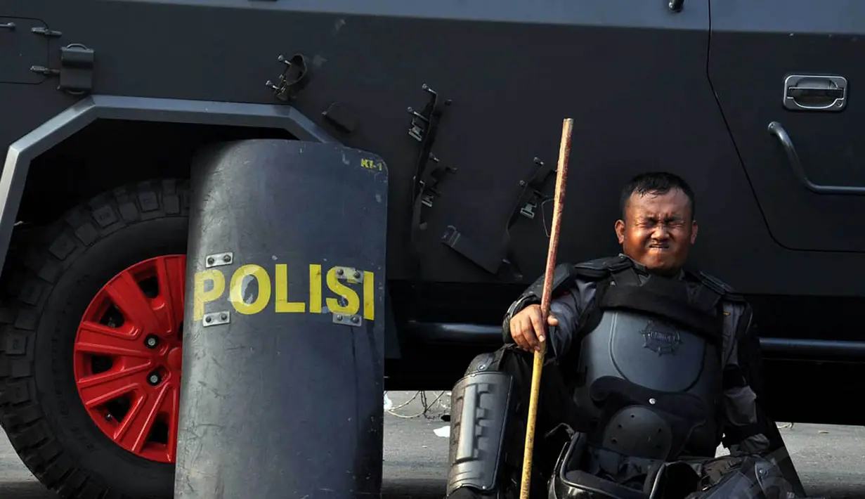 Seorang petugas yang kelelahan bersandar di mobil water cannon yang terparkir di kawasan Patung Kuda, Jakarta, Kamis (21/8/14). (Liputan6.com/Miftahul Hayat)