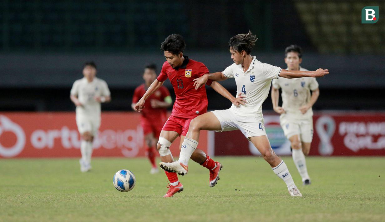 Pemain Laos U-19, Peeter Phanthavong, berusaha melewati pemain Thailand U-19 pada laga semifinal Piala AFF U-19 2022 di Stadion Patriot Candrabhaga, Bekasi, Rabu (13/7/2022). (Bola.com/M Iqbal Ichsan)