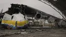 Prajurit Ukraina melewati pesawat Antonov An-225 Mriya yang hancur di bandara Antonov, Hostomel, 2 April 2022. Di pintu masuk Bandara Antonov, pasukan menjaga posisinya, tanda mereka memegang kendali penuh atas landasan pacu yang coba diserbu Rusia di hari-hari pertama perang (AP Photo/Vadim Ghirda)