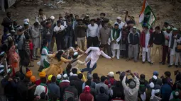 Petani India menyaksikan sekelompok wanita bermain kabbadi di lokasi protes terhadap undang-undang pertanian baru, di Ghazipur, pinggiran New Delhi, India, Kamis (9/12/2021). Petani juga membentuk komite untuk mempertimbangkan tuntutan mereka yang lain. (AP Photo/Altaf Qadri)