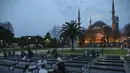 Orang-orang berbuka puasa dengan latar belakang Masjid Sultan Ahmed yang ikonik, lebih dikenal sebagai Masjid Biru, dihiasi dengan lampu dan slogan bertuliskan "Ramadhan adalah cinta," menandai bulan Ramadhan, di distrik bersejarah Sultan Ahmed di Istanbul (13/4/2021). (AP Photo/Emrah Gurel)