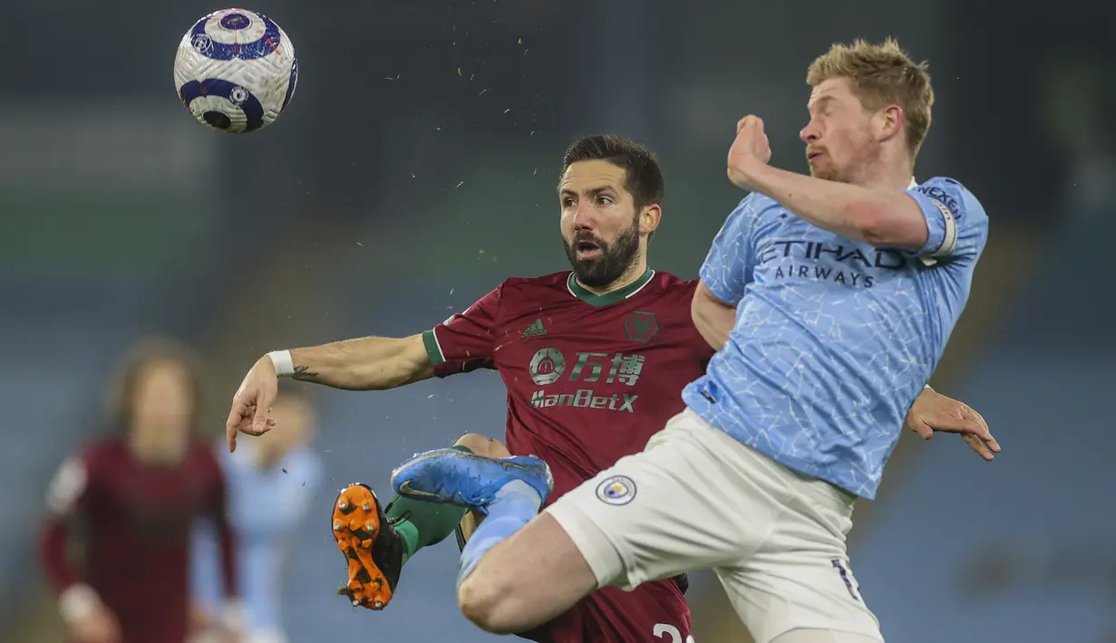 Gelandang Manchester City, Kevin De Bruyne berebut bola dengan gelandang Wolves, Joao Moutinho pada pertandingan lanjutan Liga Inggris di stadion Etihad di Manchester, Inggris, Rabu (3/3/2021).  City kini  kukuh di puncak klasemen dengan 62 poin dari 27 partai. (Carl Recine/Pool via AP)