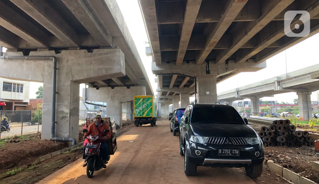 Pedagang melintasi mobil yang parkir di kolong jalan tol Becakayu di kawasan Cipinang Muara, Jakarta, Jumat (13/3/2020). Minimnya lahan parkir membuat sebagian orang tetap memarkirkan kendaraannya di kolong tol tersebut, meskipun telah terpampang larangan parkir. (Liputan6.com/Immanuel Antonius)