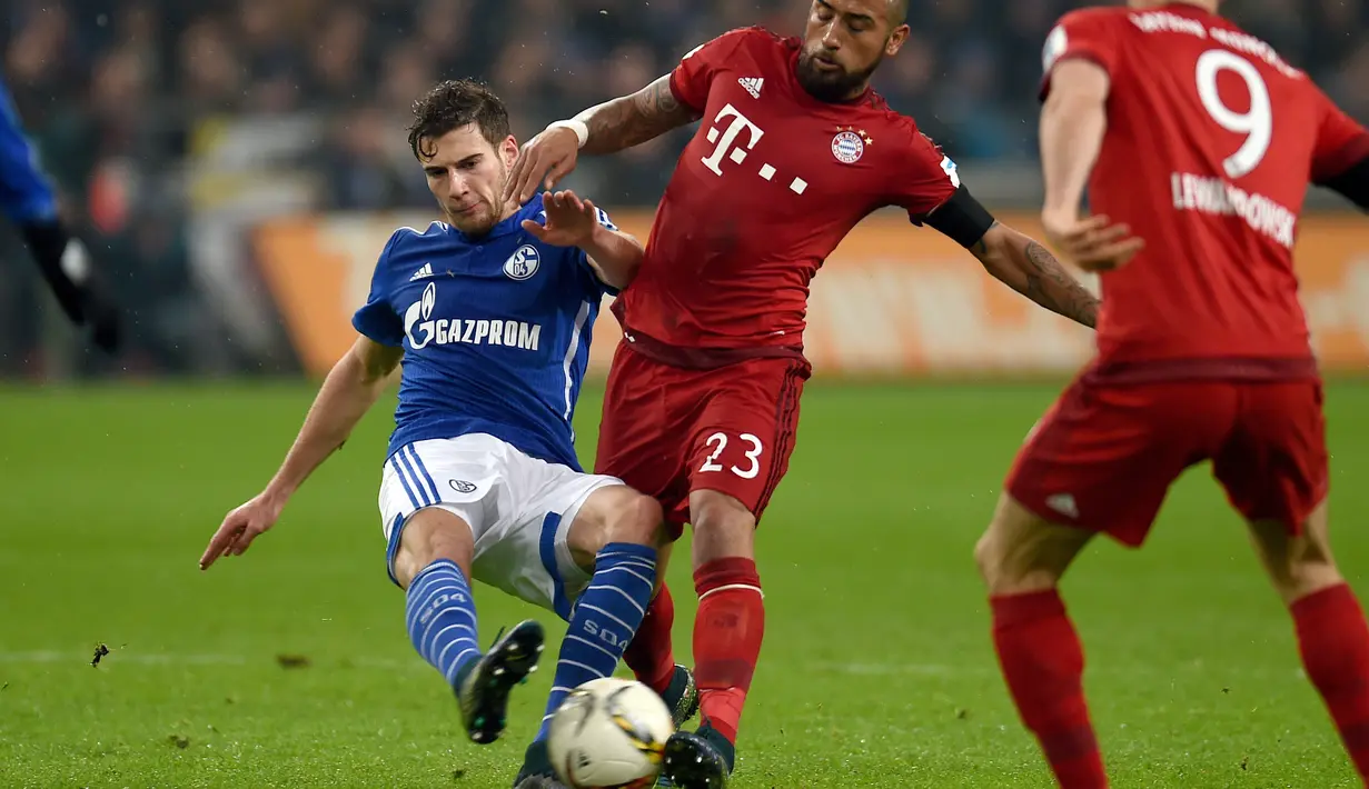 Pemain Bayern Munich, Arturo Vidal (tengah) berebut bola dengan pemain Schalke 04, Leon Goretzka pada lanjutan Bundesliga di Gelsenkirchen, Jerman,Minggu (22/11/2015) dini hari WIB. Bayern Munich  menang 3-1. (AFP Photo/Patrik Stollarz)