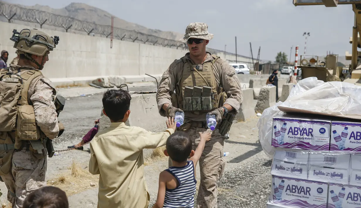 Tentara Korps Angkatan Laut AS bersama anggota Gugus Tugas Marinir Udara-Darat Tujuan Khusus di Pusat Komando, memberikan air minum kepada anak-anak saat evakuasi penduduk di bandara internasional Hamid Karzai, Kabul, Afghanistan (20/8/2021).  (Lance Cpl. Nicholas Guevara/U.S. Marine Corps via AP)