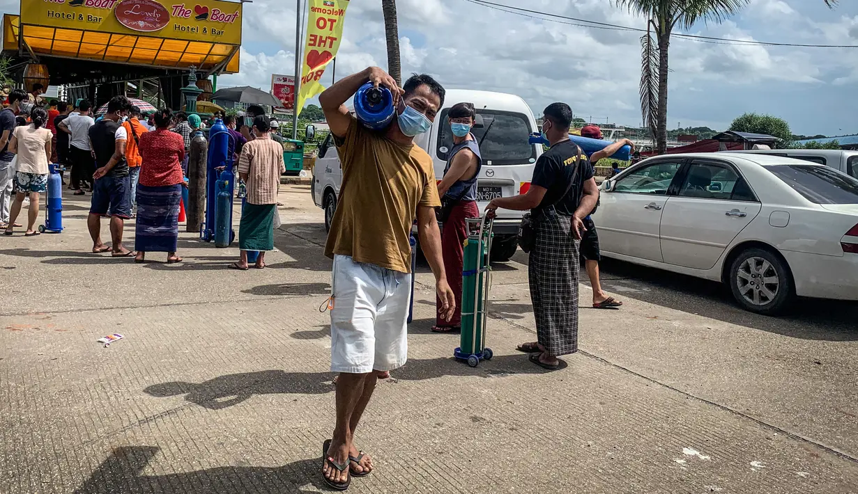 Seorang pria yang membawa tabung oksigen dari lokasi yang menyumbangkan oksigen gratis di Yangon, Myanmar pada 14 Juli 2021. Mereka putus asa mencari oksigen untuk menjaga orang yang dicintai tetap bernapas ketika gelombang corona covid-19 menerjang negara yang dilanda kudeta itu. (Ye Aung THU/AFP)