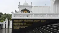 Terjemahan Surat Al-Fatihah terlihat dalam bahasa Inggris, Bahasa Indonesia dan aksara China di dinding menuju masjid Ramlie Musofa yang kosong selama bulan suci Ramadan karena pandemi virus coronavirus COVID-19 di Jakarta (4/5/2020). (AFP/Adek Berry)