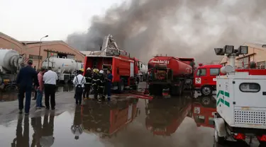 Pasukan keamanan dan pemadam berkumpul di lokasi kebakaran gudang surat suara terbesar Irak di Baghdad, Minggu (10/6). Gudang itu dilalap api sebelum dilakukan penghitungan kembali surat suara sebagaimana yang diperintahkan Parlemen. (AP/Karim Kadim)