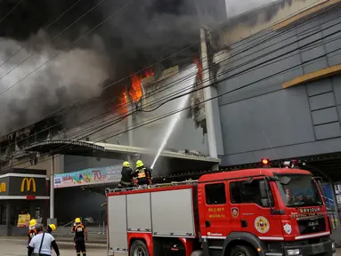 Petugas pemadam kebakaran menyiramkan air berusaha memadamkan api saat terjadi kebakaran di  kota Davao, Filipina Selatan (23/12). Dalam insiden kebakaran ini dilaporkan 40 orang tewas. (AP Photo / Manman Dejeto)
