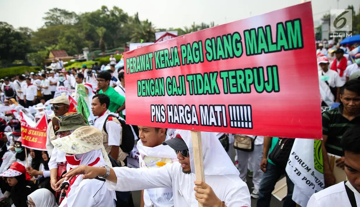 Massa membawa poster dalam aksi damai di depan Istana Negara, Jakarta, Rabu (19/7). Mereka mendesak revisi UU Aparatur Sipil Negara (ASN) yang berkeadilan agar para pegawai non PNS yang telah mengabdi bisa diangkat menjadi PNS (Liputan6.com/Faizal Fanani)