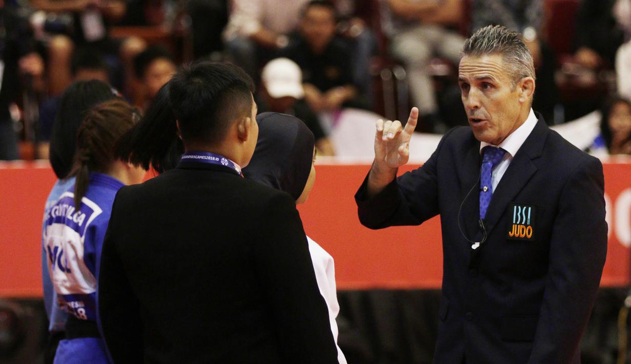 Seorang wasit meminta atlet Judo Indonesia, Miftahul Jannah, meninggalkan lokasi pertandingan pada Asian Para Games di Jiexpo, Kemayoran, Jakarta, Senin (8/10/2018). Miftah didiskualifikasi karena enggan melepas hijab nya. (Bola.com/M Iqbal Ichsan)