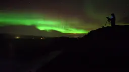 Seorang pria mengambil gambar aurora borealis atau Cahaya Utara yang terlihat di atas air terjun Godafoss di Thingeyjarsveit, Islandia, 14 Oktober 2018. Seperti halnya pelangi, Aurora Borealis memiliki gradasi warna yang beragam. (Mariana SUAREZ/AFP)