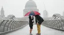 Orang-orang berlindung dengan payung di tengah hujan di London, Rabu (17/8/2022). Setelah berminggu-minggu cuaca terik, yang telah menyebabkan kekeringan dan membuat tanah kering, peringatan badai petir kuning dari Kantor Meteorologi memperkirakan hujan lebat dan badai petir yang bisa melanda bagian Inggris dan Wales. (Victoria Jones/PA via AP)