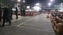 Foto yang dirilis Kamis (2/3) menunjukkan ratusan tahanan di sebuah penjara Filipina duduk dalam keadaan telanjang saat polisi melakukan penggerebekan di penjara untuk mencari barang-barang terlarang. (MERLIE DACUNOS/CEBU PROVINCIAL POLICE OFFICE/AFP)