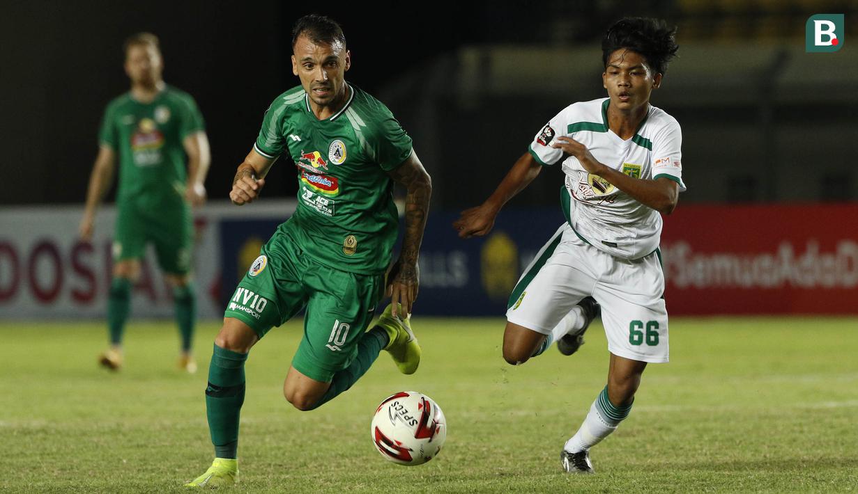 Striker PS Sleman, Velez Nicolas Leandro (kiri) menguasai bola dibayangi pemain Persebaya Surabaya, Dicky Kurniawan Arifin dalam laga Grup C Piala Menpora 2021 di Stadion Si Jalak Harupat, Bandung, Rabu (7/4/2021). (Bola.com/Ikhwan Yanuar)