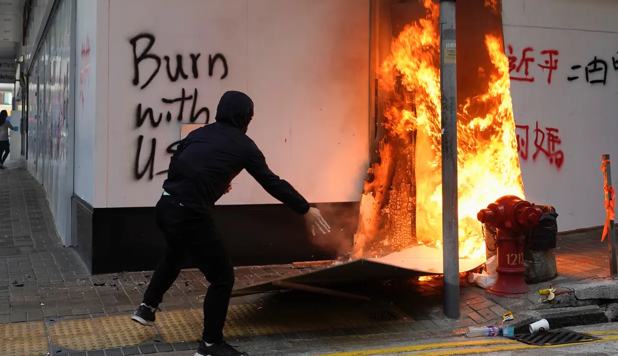 Seorang demonstran membakar kardus di luar cabang Bank of China selama protes di Distrik Central, Hong Kong, Senin (11/11/2019). Ketegangan di Hong Kong semakin meningkat setelah polisi menembak seorang demonstran hingga kritis. (AP Photo/Vincent Yu)