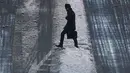 Seorang pria melintasi jalan yang tertutup salju di Tokyo (23/1). Hujan salju membuat keberangkatan penerbangan dan melumpuhkan beberapa layanan kereta api di kota tersebut. (AP Photo / Eugene Hoshiko)