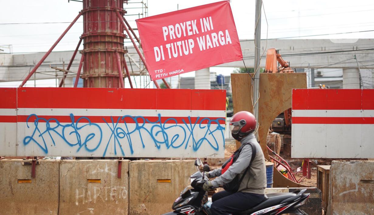 Pengguna jalan melintas di depan poster protes warga terhadap pembangunan flyover di kawasan Tanjung Barat, Jakarta, Rabu (15/7/2020). Dalam poster protes tersebut, warga menuntut agar pembayaran pelunasan pembebasan lahan segera diselesaikan secara serentak. (Liputan6.com/Immanuel Antonius)