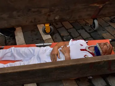 Seorang peserta ditandu tim medis setelah diseruduk banteng dalam Festival San Fermin di Pamplona, Spanyol utara, (9/7). Ratusan orang dari seluruh dunia  setiap tahunnya ambil bagian dalam Festival Adu Banteng, San Fermin. (AP Photo/Alvaro Barrientos)
