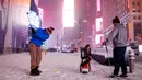 Dua pria bermain golf dengan bola tenis saat badai salju melanda kawasan Times Square, New York, (14/3). NWS menetapkan status darurat untuk negara bagian New York dan New Jersey yang terancam dilanda badai salju. (AP/Mark Lennihan)