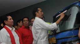 Didampingi Teten Masduki dan Sutiyoso, Jokowi menandatangani Bajaj bernomor polisi B 2954 WA itu dengan tinta berwarna emas, Minggu (1/6/14). (Liputan6.com/Herman Zakharia)