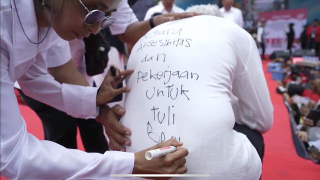Disabilitas rungu bernama Nabila menitipkan pesan kepada Ganjar Pranowo melalui tulisan tangan di balik punggung kemeja putihnya saat kampanye di Pangreh Praja Sepinggan, Balikpapan Selatan, Kalimantan Timur, Selasa (6/2/2024).