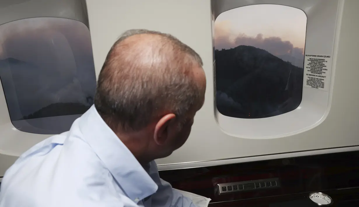 Presiden Turki Recep Tayyip Erdogan melihat dari pesawatnya ke kebakaran hutan di Marmaris, Mugla, Turki (31/7/2021). Kebakaran di seluruh Turki sejak Rabu membakar hutan, merambah desa dan tujuan wisata dan memaksa orang untuk mengungsi. (Turkish Presidency via AP, Pool)