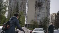 Orang-orang melewati sebuah gedung apartemen yang rusak akibat drone yang ditembak jatuh, selama serangan semalam Rusia, di Kyiv, Ukraina, Senin, 8 Mei 2023. (AP Photo/Andrew Kravchenko)