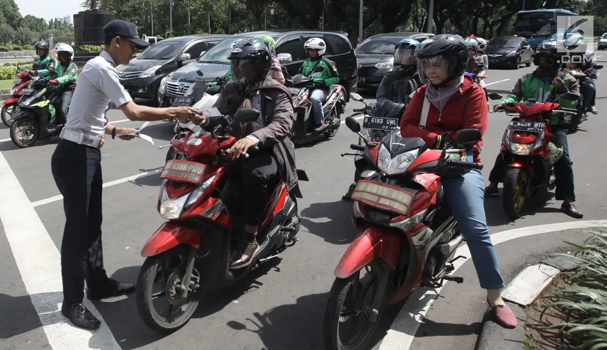 Petugas Dishub DKI Jakarta membagikan selebaran yang berisi sosialisasi lajur khusus sepeda motor di Jalan MH Thamrin, Jakarta, Senin (29/1). (Liputan6.com/Arya Manggala)