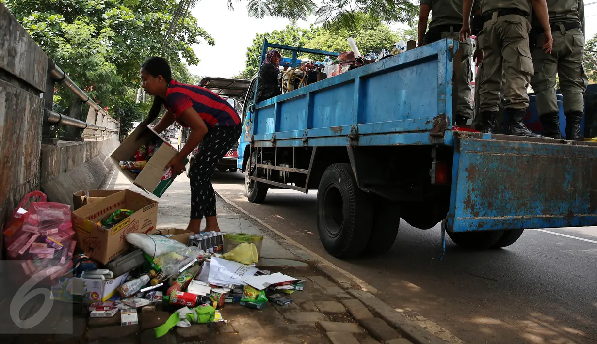 Seorang Pedagang merapikan barang daganggannya saat Petugas Satpol PP menertibkan lapak pedagang kaki lima (PKL) di pinggir jalan Kawasan Palmerah, Jakarta, Senin (17/10). Aktifitas ini dilakukan Satpol PP kelurahan Gelora. (Liputan6.com/Johan Tallo)