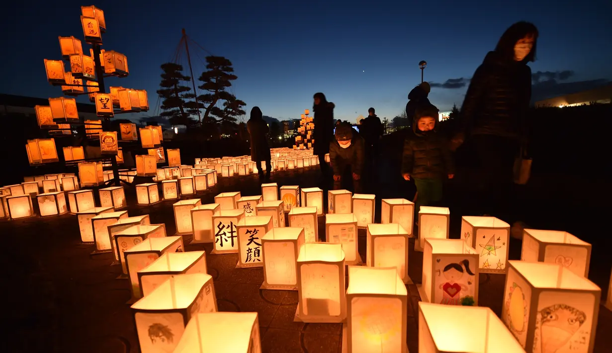Pengunjung melihat lentera kertas saat upacara peringatan bencana gempa tsunami yang terjadi pada tahun 2011 di Natori, Prefektur Miyagi, Jepang (11/3). (AFP/Kazuhiro Nogi)