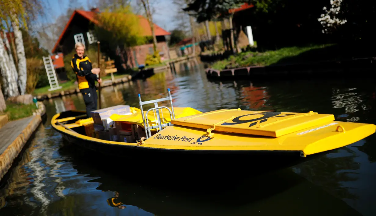 Tukang pos wanita dari Deutsche Pos DHL, Andrea Bunar menggunakan perahu tradisional untuk mengantar surat dan paket di desa Spreewald di Lehde, Jerman, 4 April 2019. Andrea Bunar menggunakan perahu untuk mengantar surat setiap bulan April hingga Oktober. (REUTERS/Hannibal Hanschke)